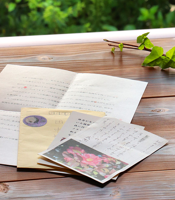 お客様から戴いたハガキを持つ田中夫妻